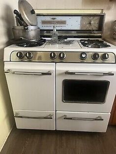 an old fashioned white stove and oven in a kitchen with wood flooring on the walls