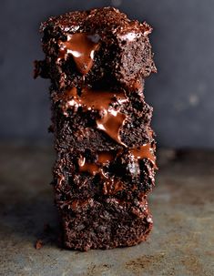 three chocolate brownies stacked on top of each other with one piece cut in half