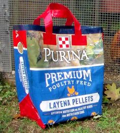 a blue and red bag sitting on the ground in front of a chicken pen with chickens behind it