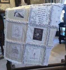 a baby quilt hanging from a rail in a room with pictures and writing on it