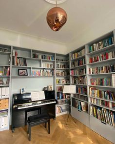 a room filled with lots of books and a piano in front of a book shelf