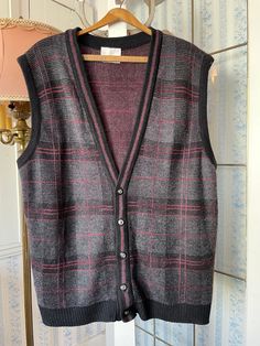 This comfy vest from London Fog is made of 100 per cent acrylic in dark grey, black and burgundy red. It has the original decorative buttons in the front. Marked size extra large. The measurements, taken with the vest lying flat, are: shoulder to shoulder, 18 inches; armpit to armpit, 24 inches; length, 26 1/2 inches; bottom edge, 20 inches (with stretchy ribbing). The vest overall has a bit of stretch. In good vintage condition. Affordable Gray Fitted Vest, Fitted Black Sweater Vest, Classic Plaid Vest For Fall, Plaid Vest For Fall, Classic Black Sweater Vest For Fall, Plaid Sleeveless Vest For Fall, Classic Black Sweater Vest For Winter, Black Sleeveless Wool Top, Fitted Wool Sweater Vest In Black