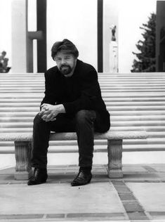 a man sitting on top of a bench in front of a set of stone steps