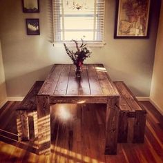 a wooden table sitting on top of a hard wood floor in front of a window