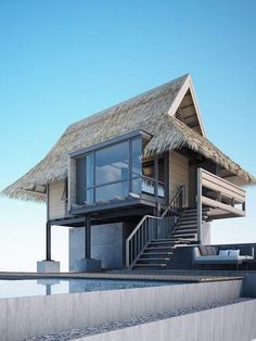 a house with a thatched roof next to the ocean and stairs leading up to it