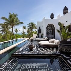 an outdoor pool with black and white tiles on the floor, surrounded by palm trees