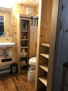 a bathroom with wooden walls and flooring next to a white toilet in a small room