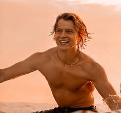 a shirtless young man is playing in the water