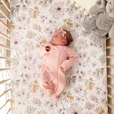 a baby is laying down on a floral wallpaper