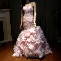 a mannequin wearing a pink dress in front of a fireplace