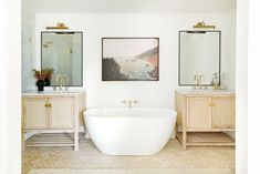 a large white bath tub sitting under two mirrors