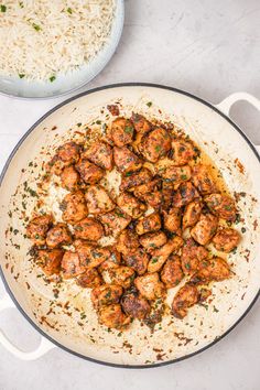 a pan filled with meat and rice next to another pan full of food on the table