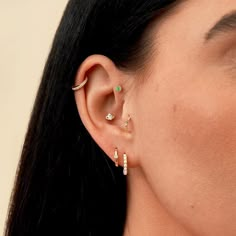 a woman wearing three different types of ear piercings on her left ear and right ear