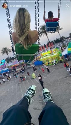 two people sitting on swings at an amusement park