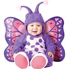 a baby sitting on the ground wearing a purple butterfly costume with polka dots and hearts