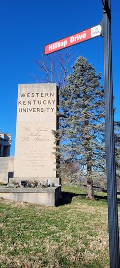 a street sign in front of a tree and building with a name on it that reads western kentucky university