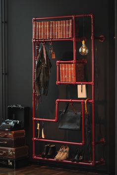 a red rack with shoes and purses on it in front of a black wall