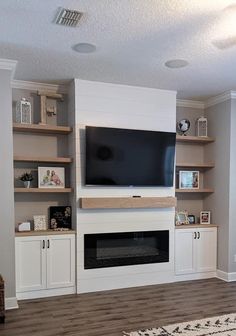 a living room with built in shelves and a flat screen tv mounted on the wall