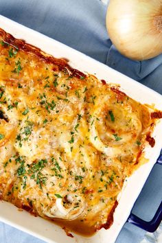 a casserole dish with cheese, onions and parsley on the side next to an onion