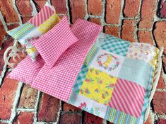 four different colored patchwork quilts on a white tablecloth with red brick wall in the background