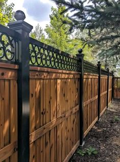 a wooden fence with wrought iron fencing around it and trees in the backgroud