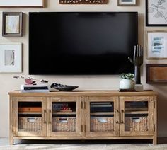 a flat screen tv mounted to the side of a wooden entertainment center with wicker baskets