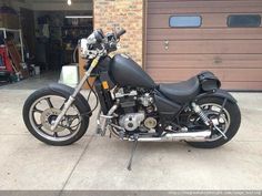 a black motorcycle parked in front of a garage