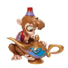 a monkey figurine sitting on top of a teapot with a spoon in it