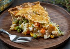 a piece of pie on a wooden plate with a fork and bowl in the background