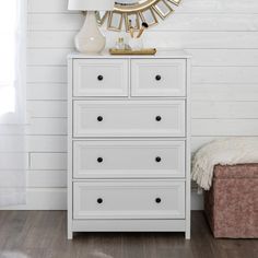 a white chest of drawers with a mirror above it and a lamp on the side