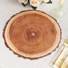 a wood slice with flowers and candles on the table in front of it, along with other items