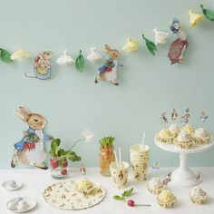 a table topped with cakes and cupcakes covered in frosting next to bunting