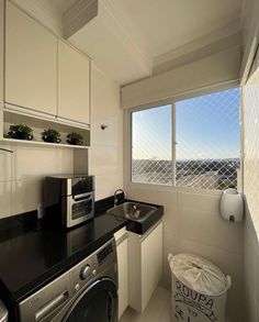 a kitchen with black counter tops and white cupboards next to a window that looks out onto the ocean