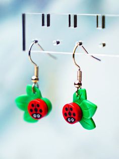 two red and green ladybug earrings hanging from hooks