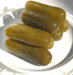 three pickles sitting on top of a white plate