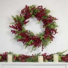 a christmas wreath is hung on the mantle with candles