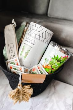 coffee mugs and other items in a black basket on a marble counter top with a tassel hanging from the handle