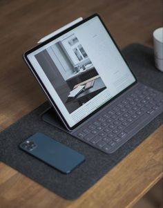 an open laptop computer sitting on top of a wooden table next to a coffee cup