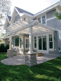 a white pergolan sitting in front of a gray house