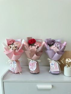 three bouquets of flowers sitting on top of a white dresser next to each other