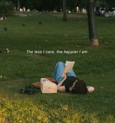 a person laying on the grass reading a book with birds in the background that reads, the less i care, the happier i am