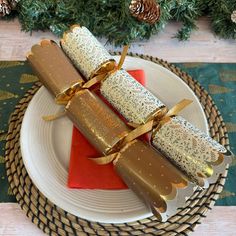 three pieces of food wrapped in gold ribbon sitting on a plate next to a christmas tree