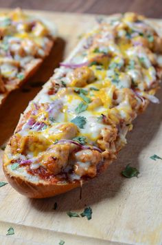 bread with meat and cheese on it sitting on a cutting board