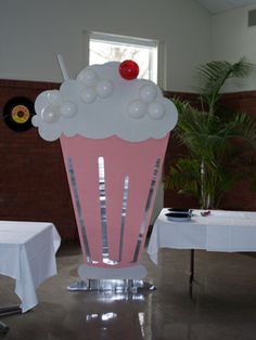 a pink cupcake with white frosting sitting on top of a table in a room