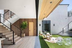 the inside of a modern house with grass and wood flooring, stairs leading up to the second floor