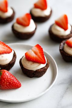 chocolate cupcakes with whipped cream and strawberries on a white plate, ready to be eaten