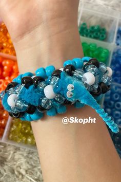 a person wearing a bracelet made out of blue beads and black, white, and grey beads