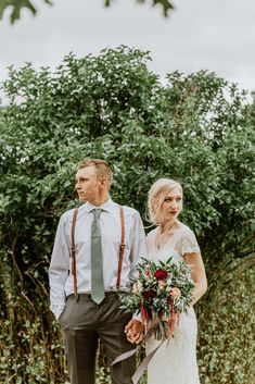 the bride and groom are standing together in front of some greenery at their wedding