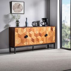 a sideboard with wooden panels and black handles in a room next to a window