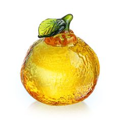 an orange glass vase sitting on top of a white surface with a green leaf sticking out of it